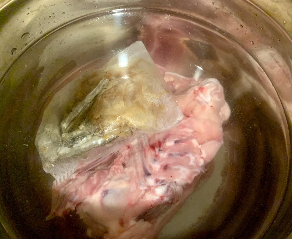 だしパックと冷凍鶏ガラを鍋で煮込む